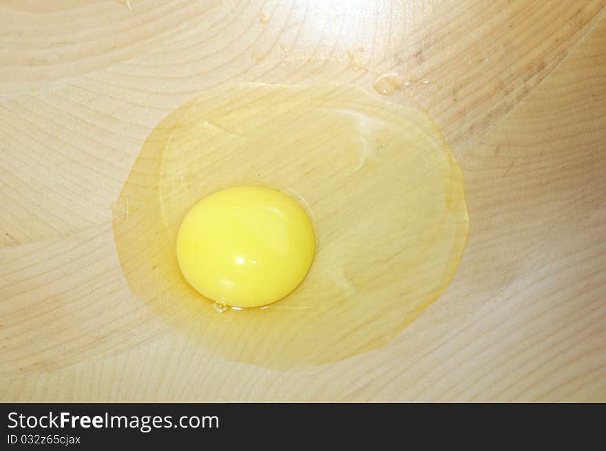 A broken egg in a wooden bowl