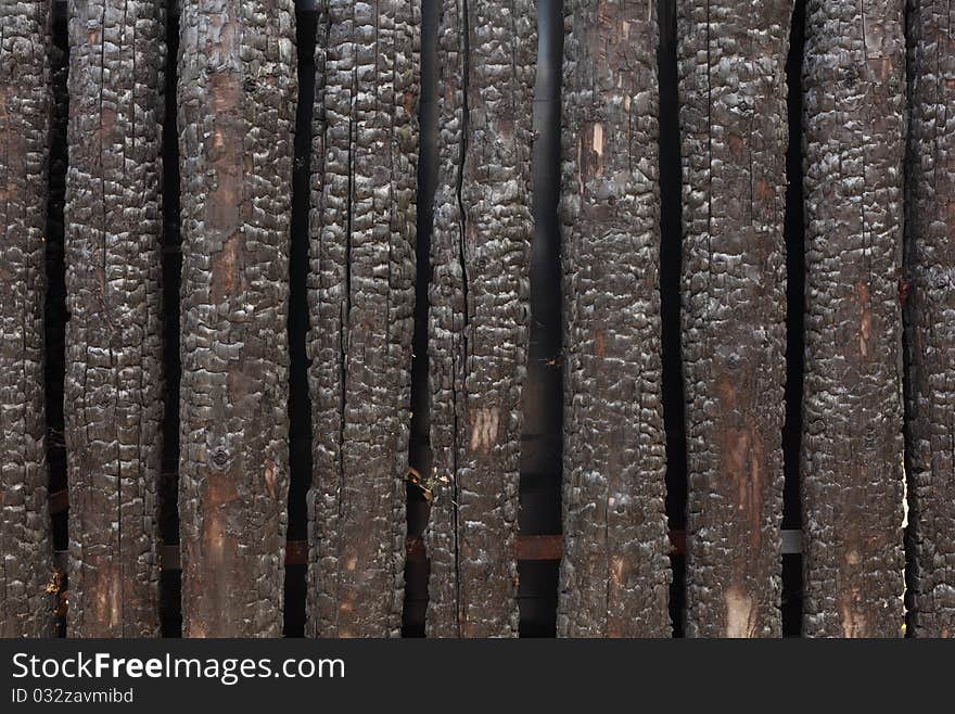 A burned charred wooden fence. A burned charred wooden fence.