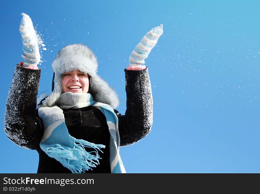 Woman making snowfall against blue sky