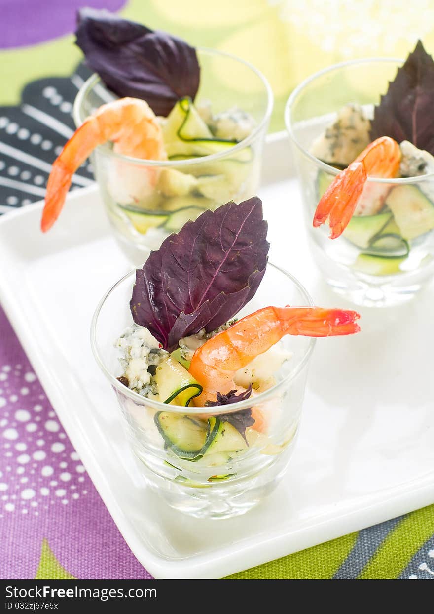 Tasty prawns appetizer with zucchini, cheese and basil in glass