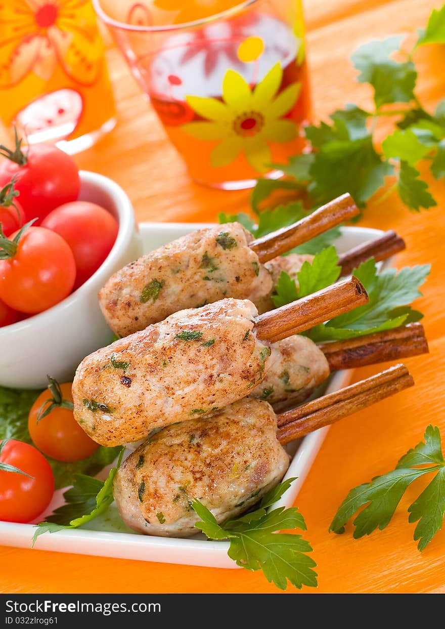 Pork (or chicken) kebab on cinnamon stickst with salad and tomatoes