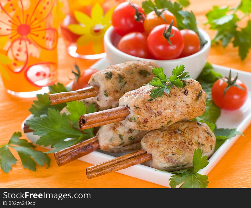 Pork (or chicken) kebab on cinnamon stickst with salad and tomatoes