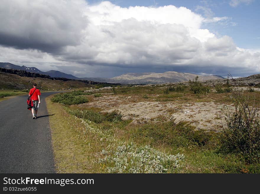 Lonely male traveller walking along the street and hitch-hiking  in Iceland