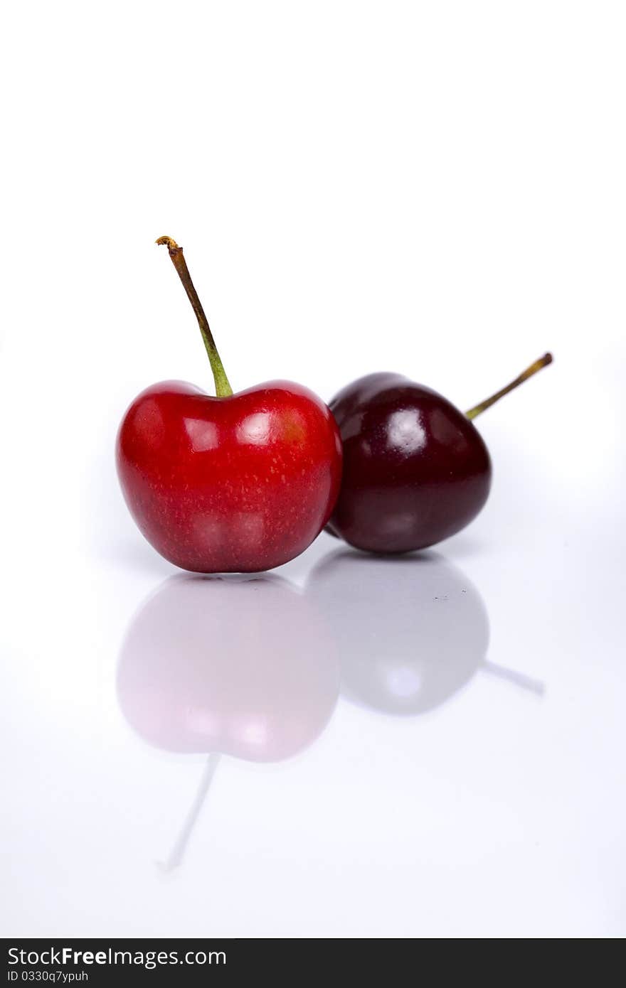 Two fresh cherries isolated on white background with reflection in foreground.