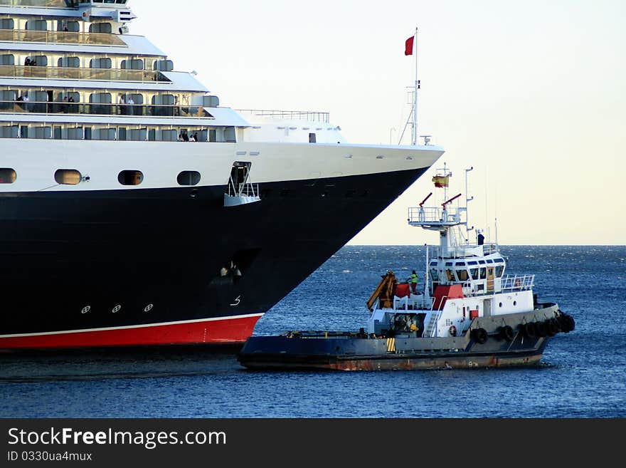 Luxury cruise with a tug going out ofport