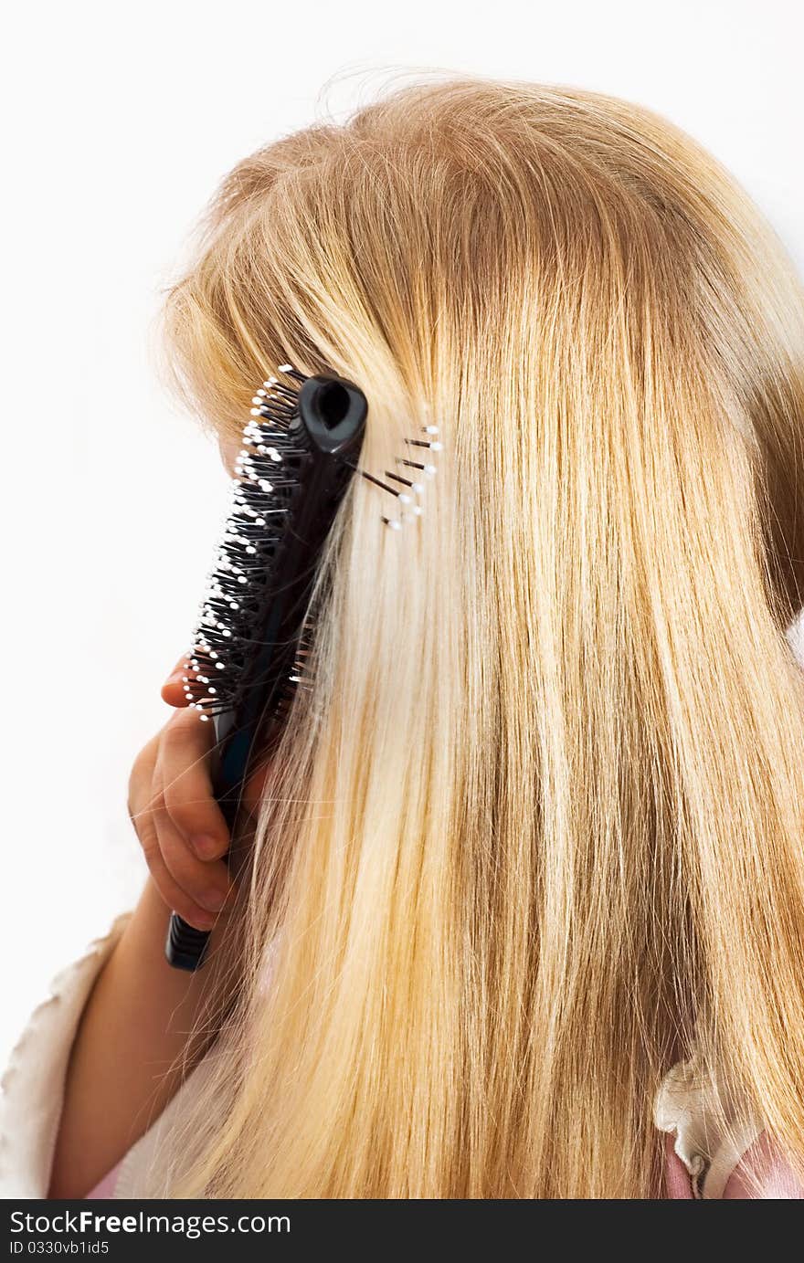 Little girl combing her hair, a white background