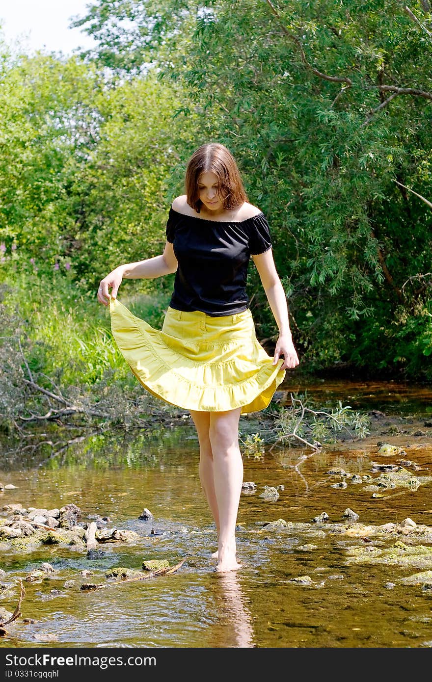 Young woman crossing little stream in forest. Young woman crossing little stream in forest