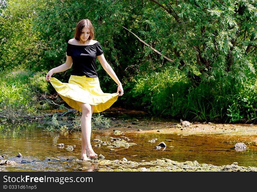 Young woman crossing little stream in forest. Young woman crossing little stream in forest