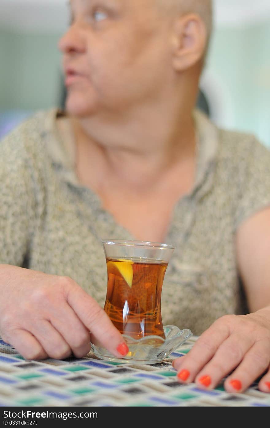 A woman holds a glass of tea in order to drink. A woman holds a glass of tea in order to drink