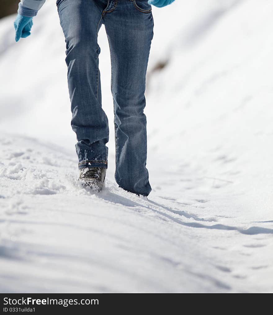 Pretty young woman walking in deep snow on a sunny winter day