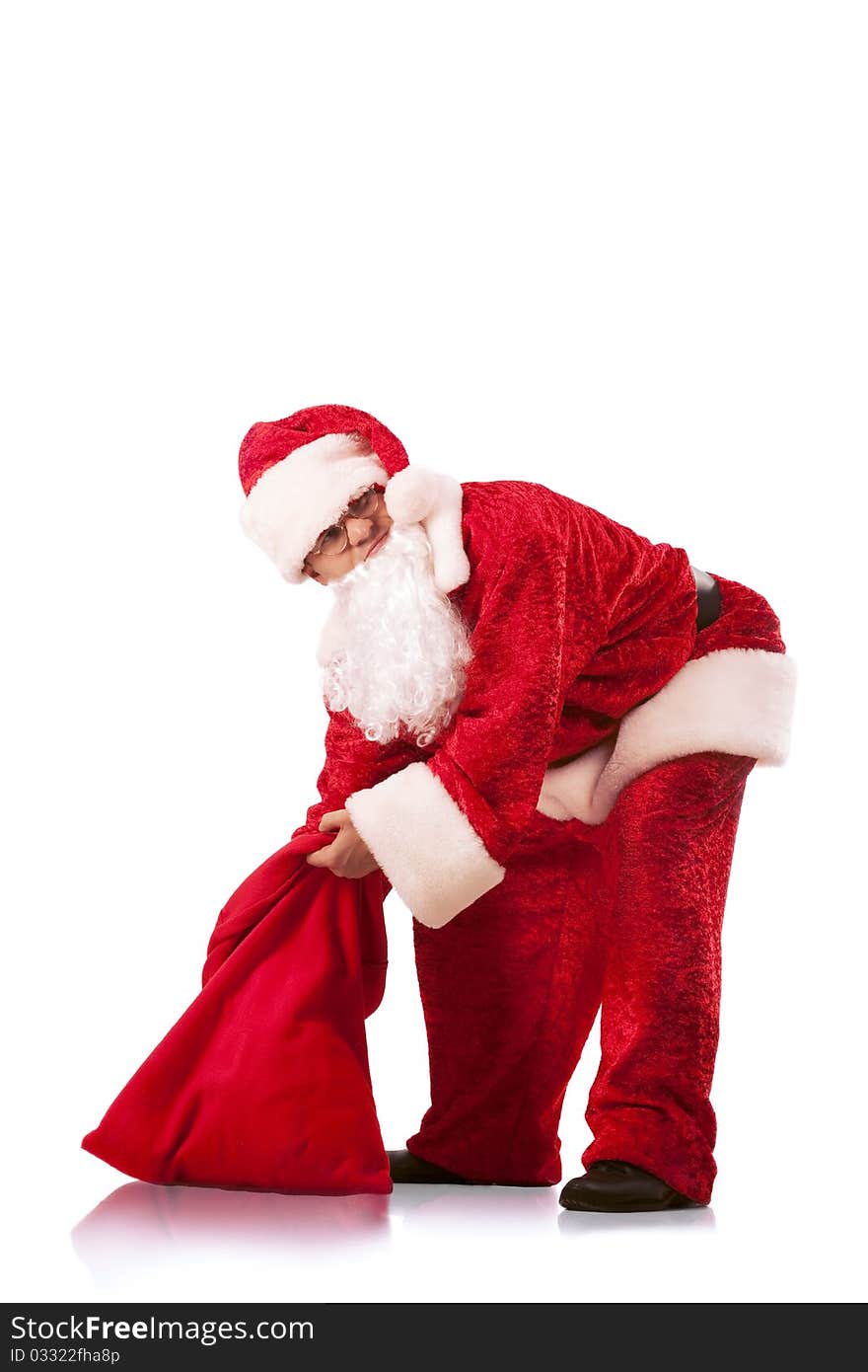 Funny Santa Clause carrying a heavy sack with gifts. Isolated on white.