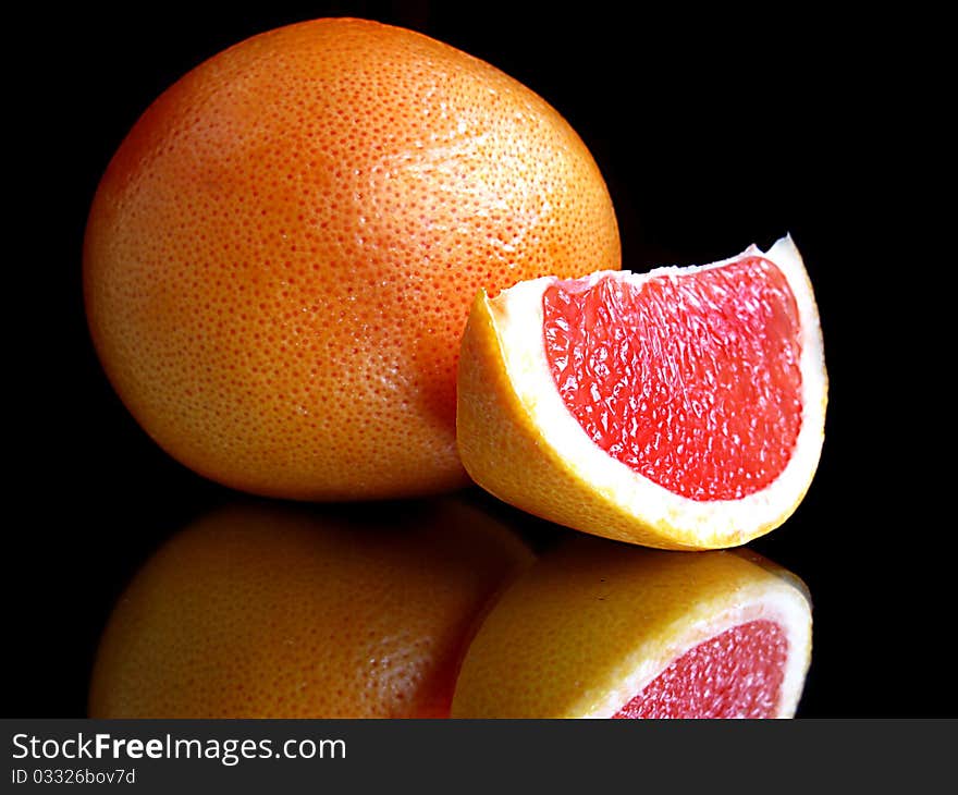 Grapefruit with segment and mirror isolated on black. Grapefruit with segment and mirror isolated on black