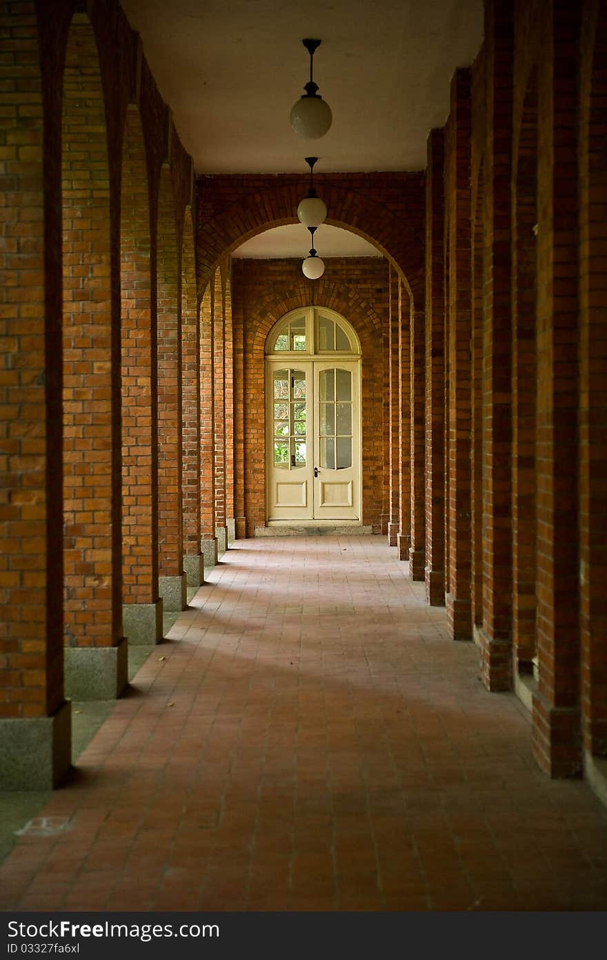 A hallway of a red brick building with sunlight shining in from the left. A hallway of a red brick building with sunlight shining in from the left.