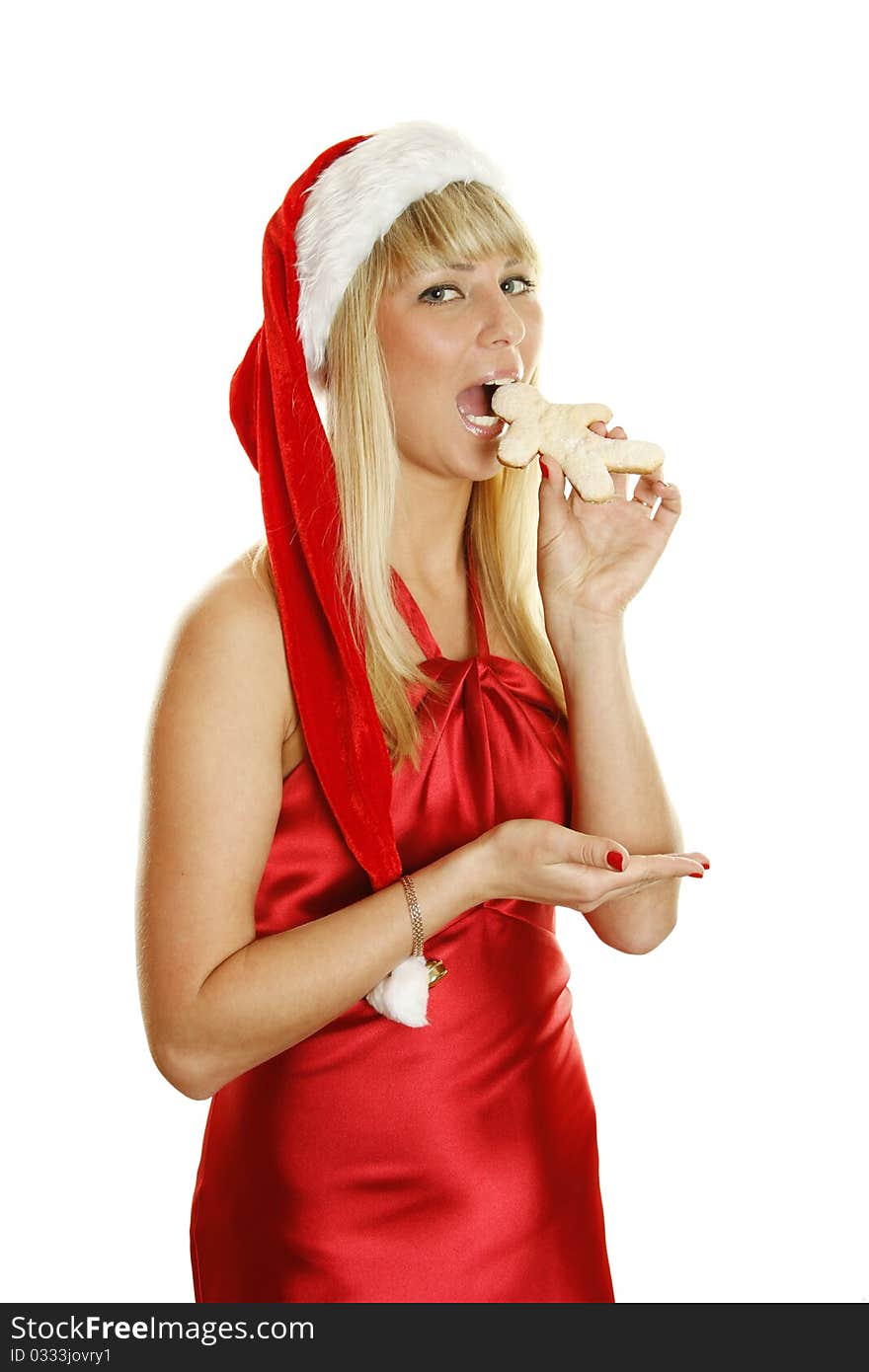 Beautiful girl in a red dress and hat Santa with gingerbread men. Tries to bite him. Isolated on a white background. Beautiful girl in a red dress and hat Santa with gingerbread men. Tries to bite him. Isolated on a white background