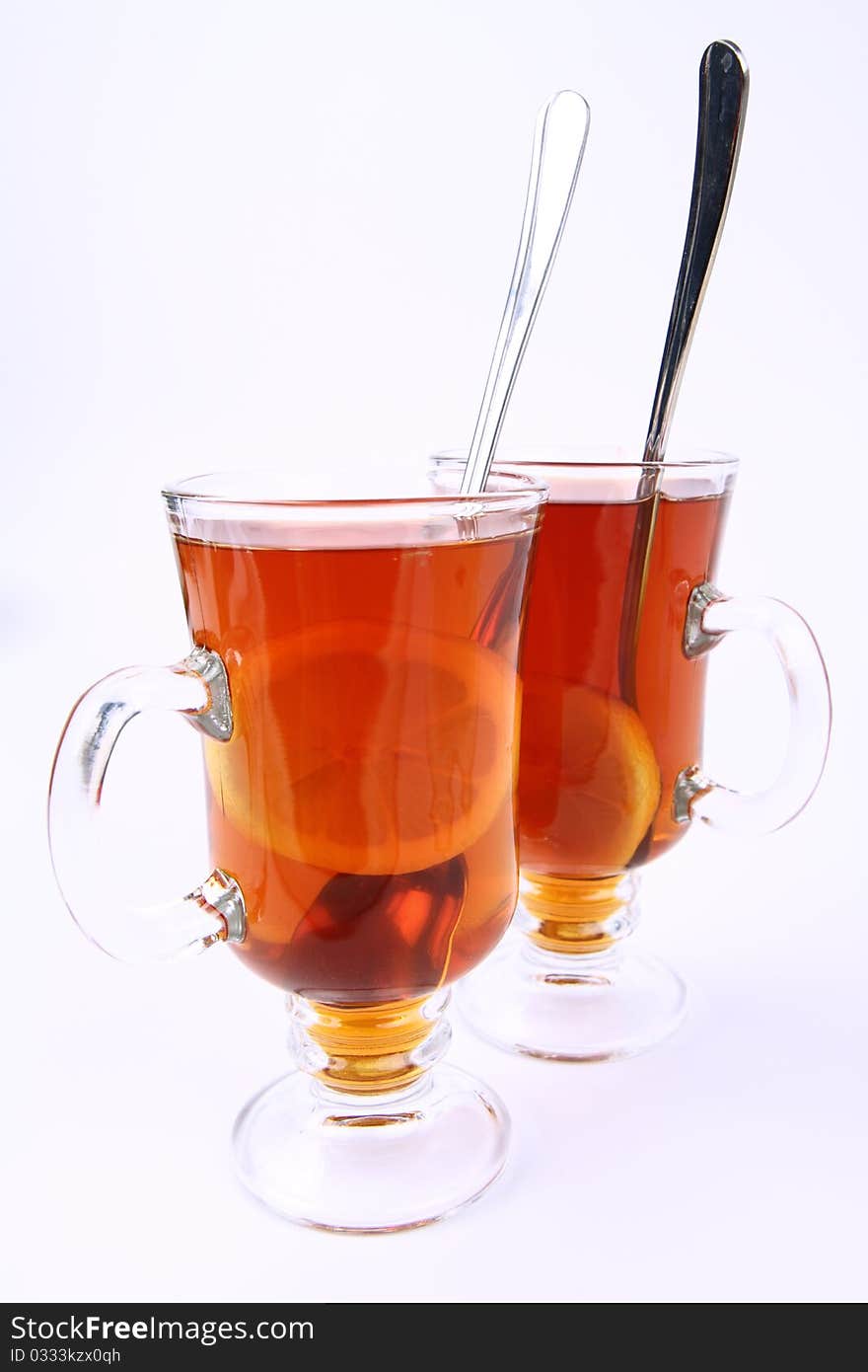 Two glasses of tea with lemon on white background