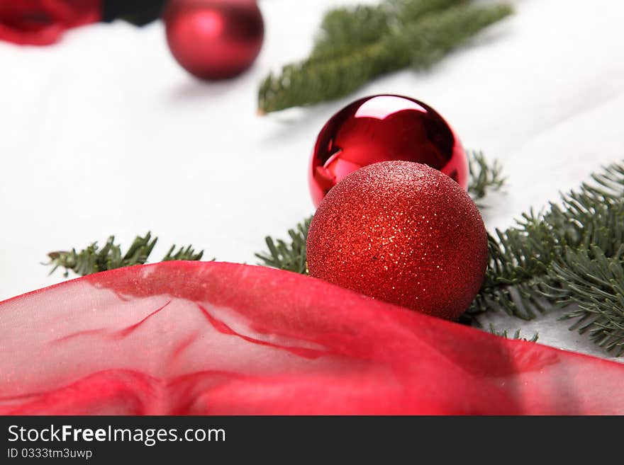 A Christmas bauble in snow with a green twig