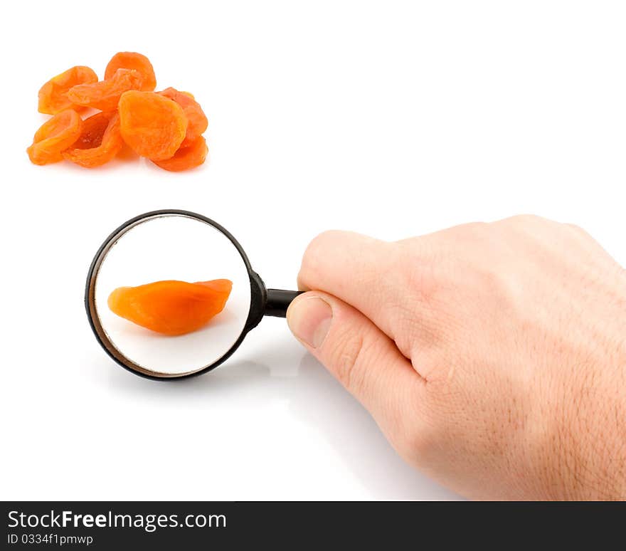 Dried apricots under a magnifying glass on a white background. Dried apricots under a magnifying glass on a white background.