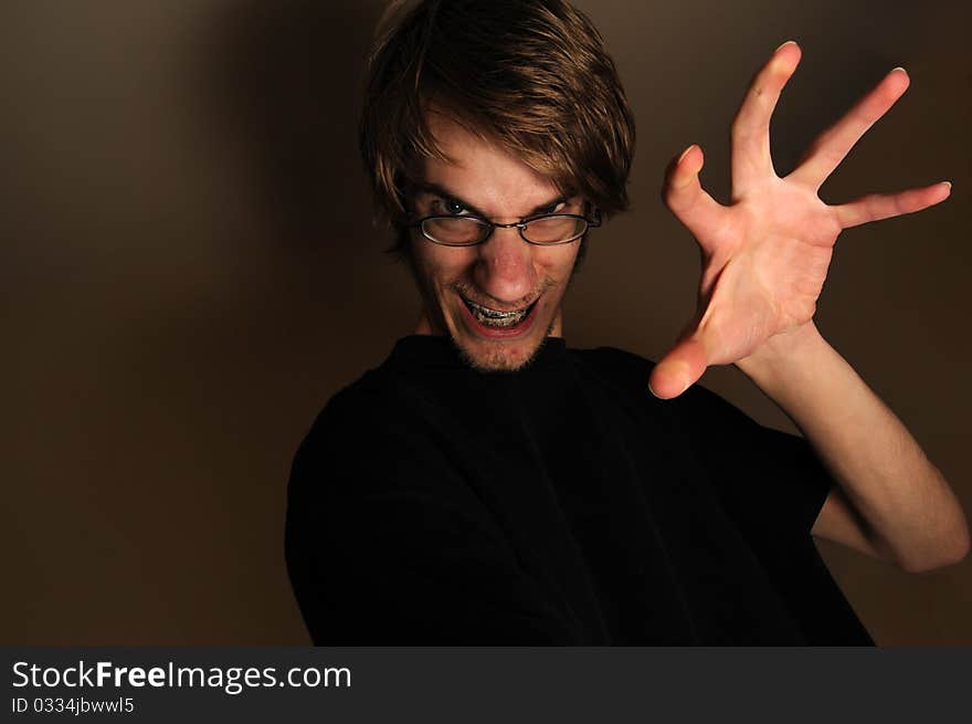 Young man ready to grab, touch, or something with his large hand claw. He looks like a techie with his glasses and braces on, but can qualify as any sort of regular person being scary. Young man ready to grab, touch, or something with his large hand claw. He looks like a techie with his glasses and braces on, but can qualify as any sort of regular person being scary.