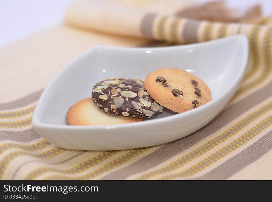 Delicious cookies and biscuits on white plate and color background