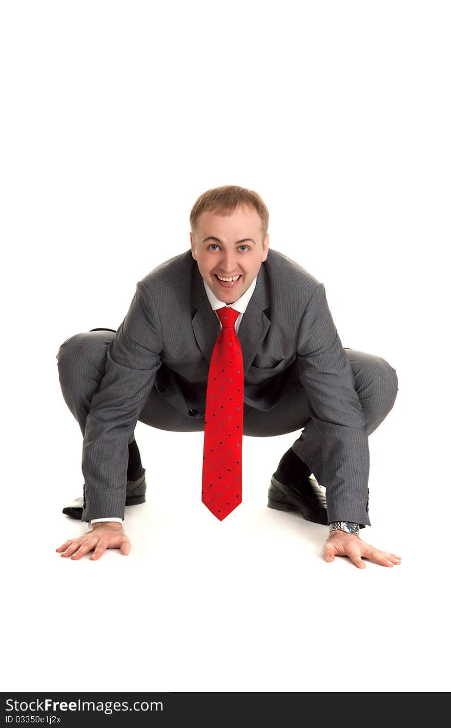 Man in gray suit and red tie sits in pose to frog