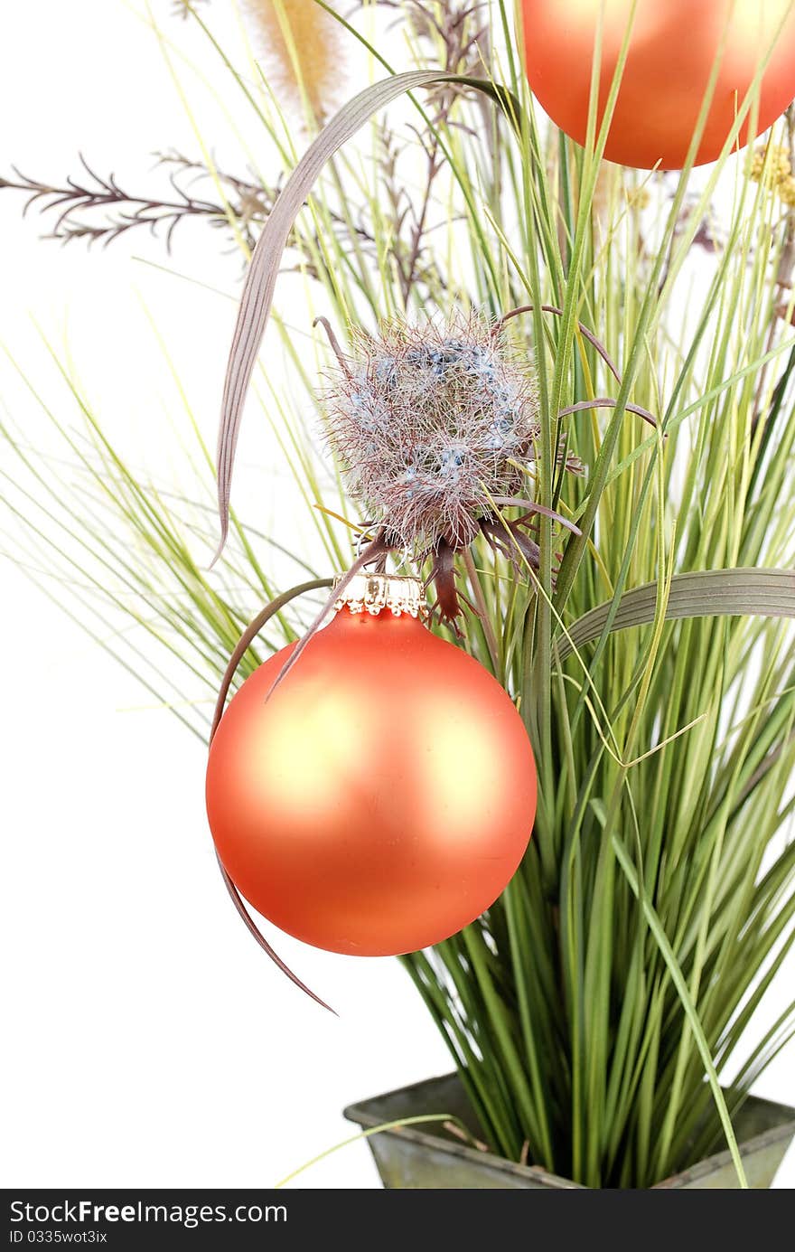 Bunch with artificial grass and blue flowers in metal vase decorated with Christmas orange balls isolated on the white background.Closeup. Bunch with artificial grass and blue flowers in metal vase decorated with Christmas orange balls isolated on the white background.Closeup.