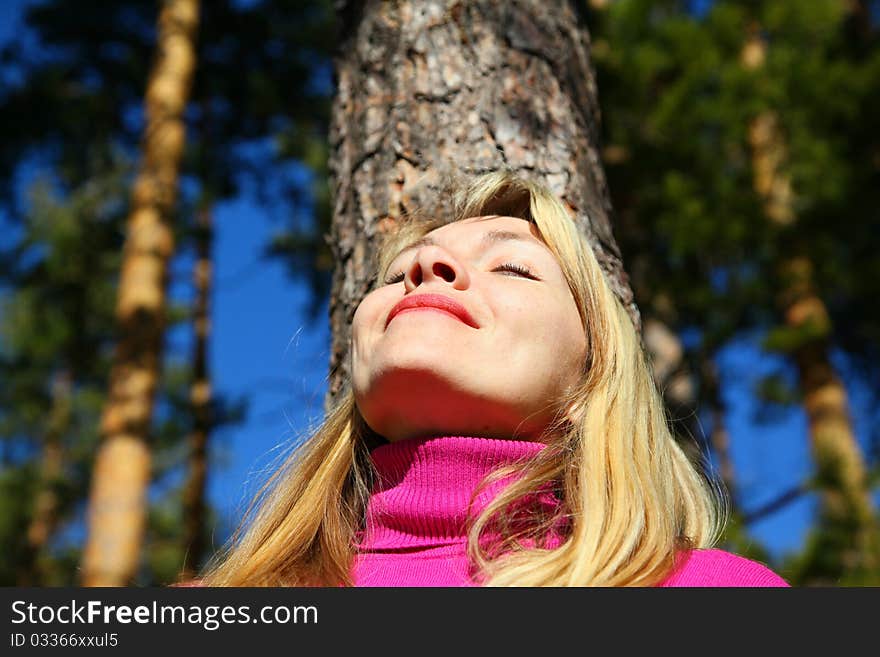 Beauty woman breathes near trunk of pine