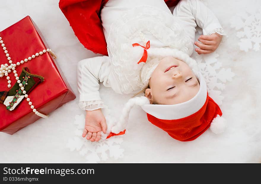 The little girl sleeps near to a New Year's gift. The little girl sleeps near to a New Year's gift