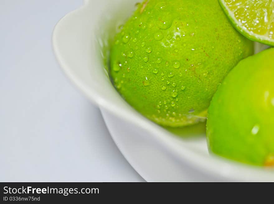 Fresh green lemon in a white porcelain bowl