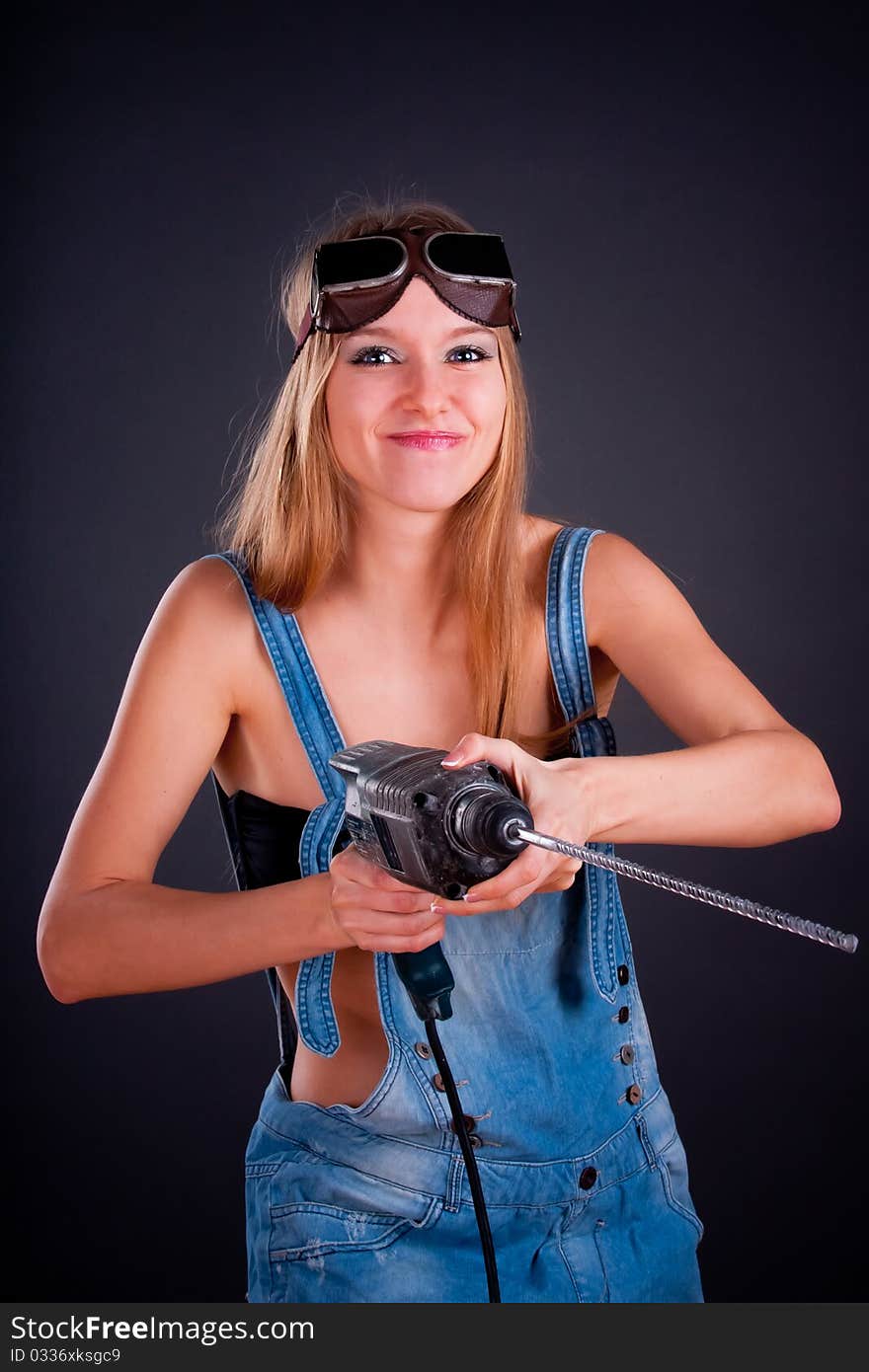 Girl with a drill in building overalls