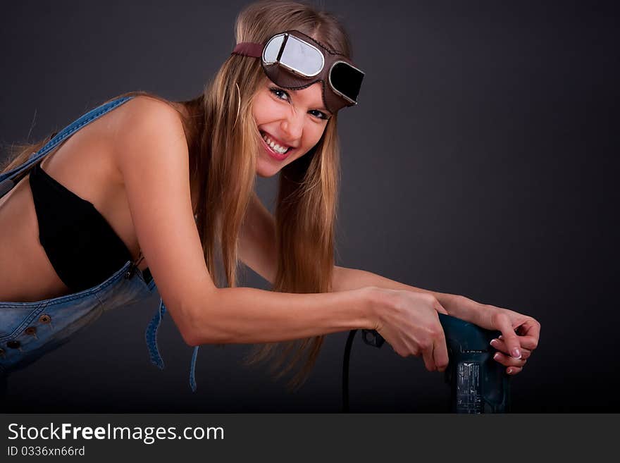 Girl with a drill in building overalls