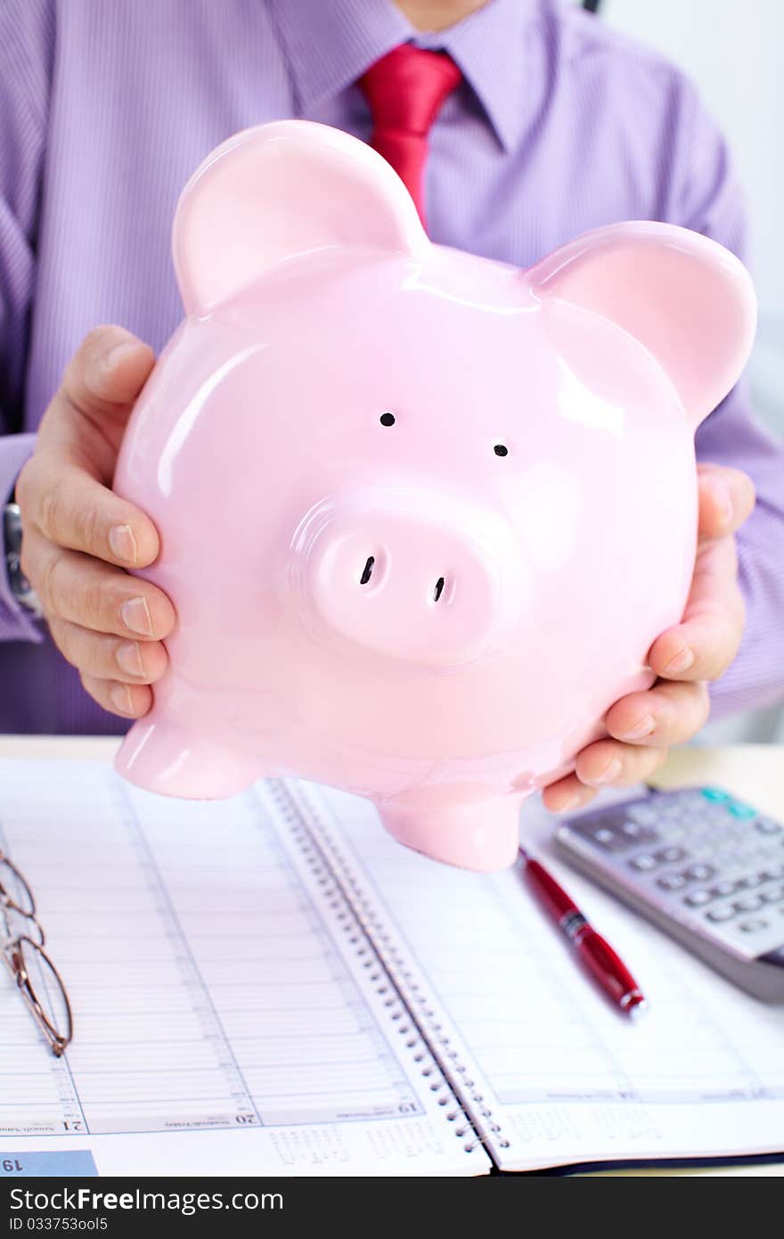 Businessman holding a pink pig bank. Businessman holding a pink pig bank