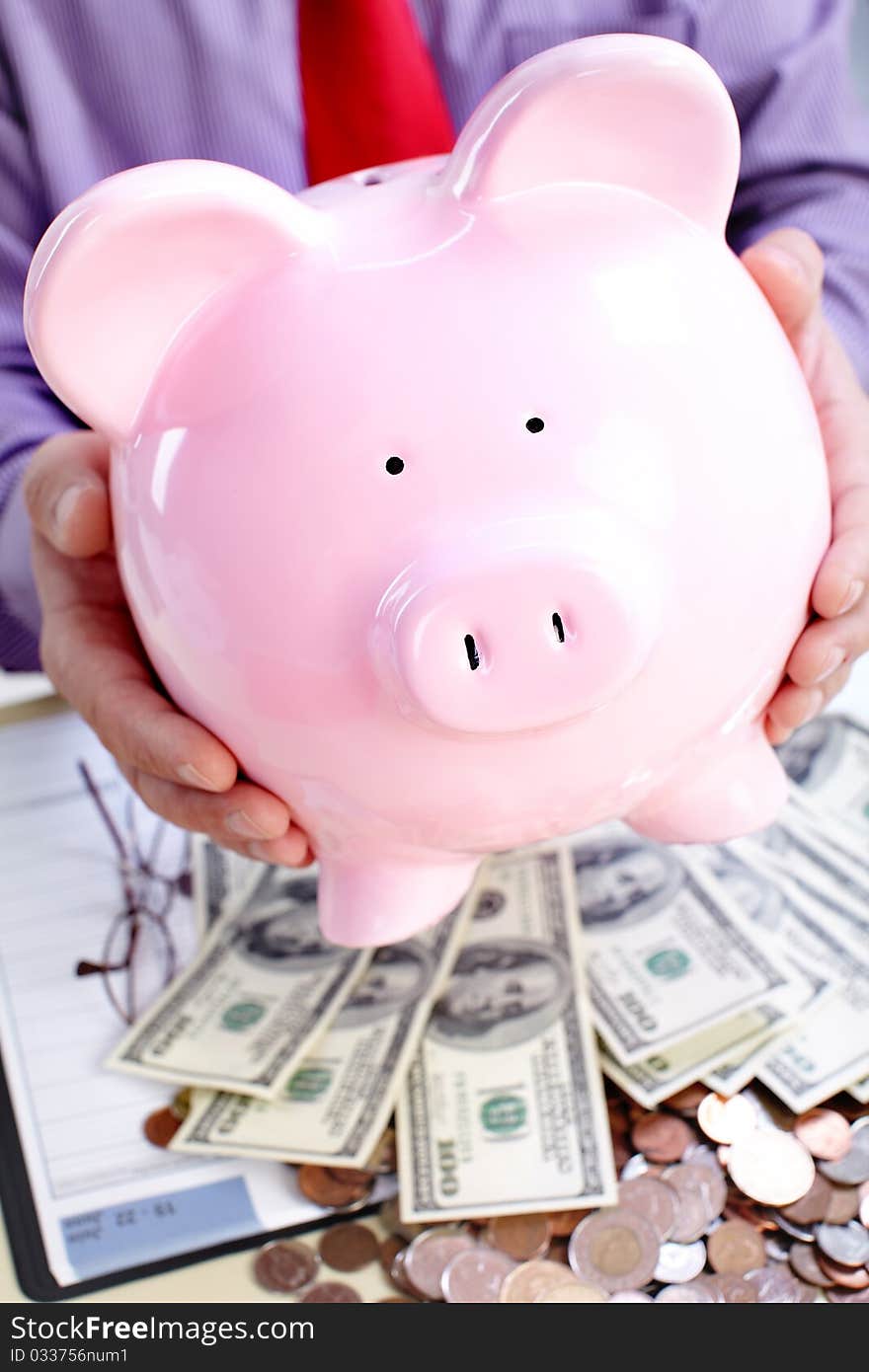 Businessman holding a pink pig bank. Businessman holding a pink pig bank