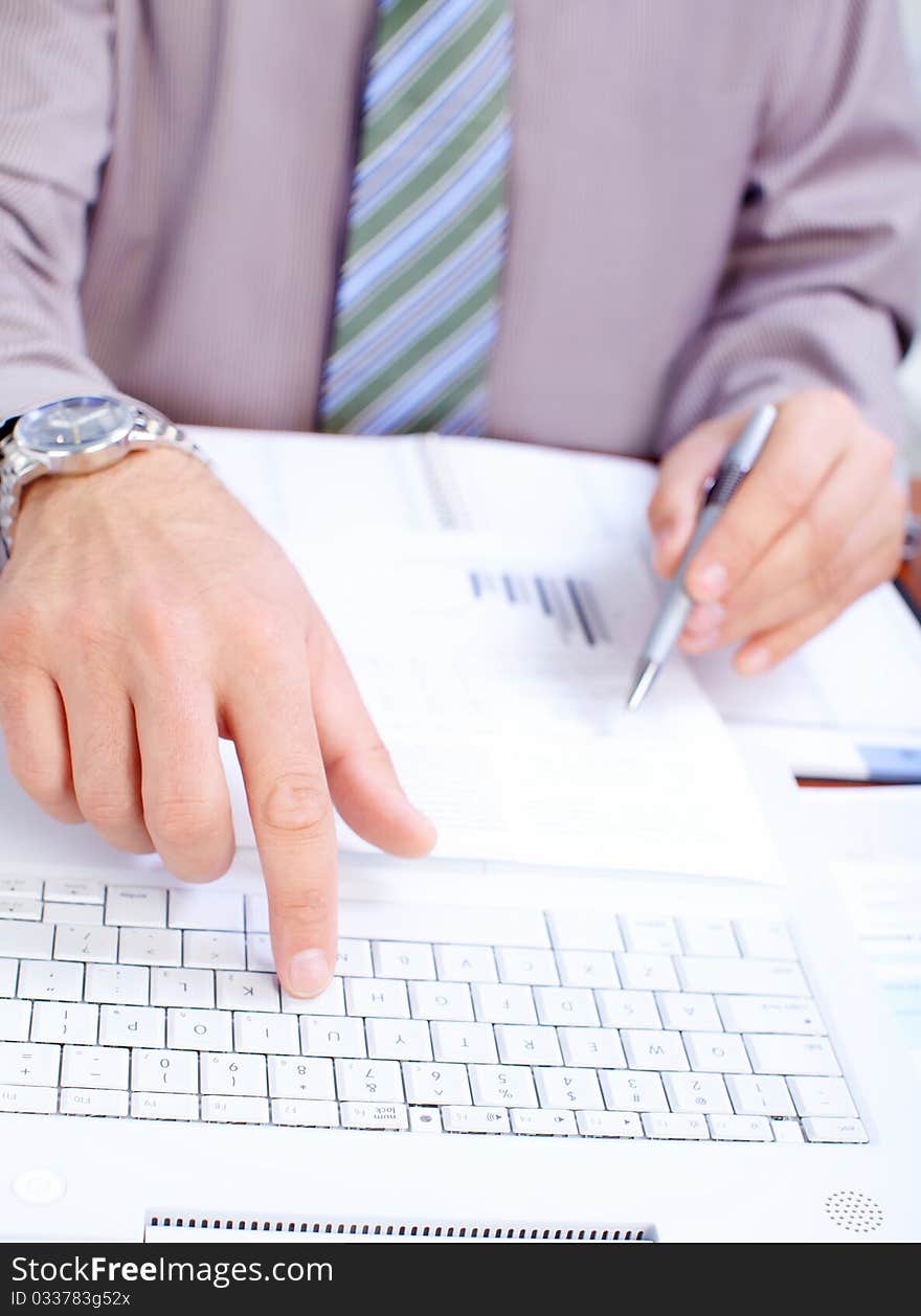 Businessman typing on a white laptop in office