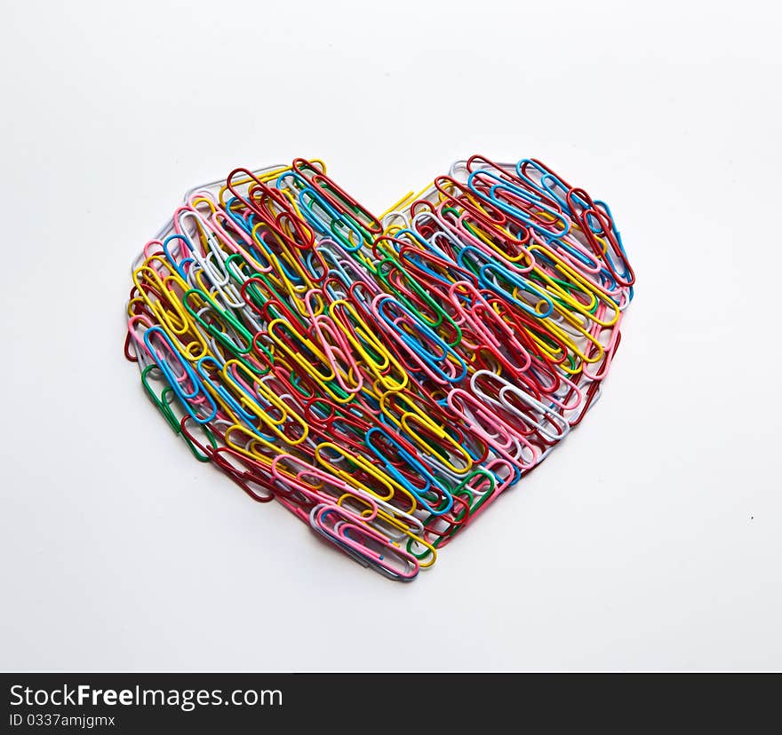 Multi coloured paper clips arraged in heart shape on isolated white background. Multi coloured paper clips arraged in heart shape on isolated white background.