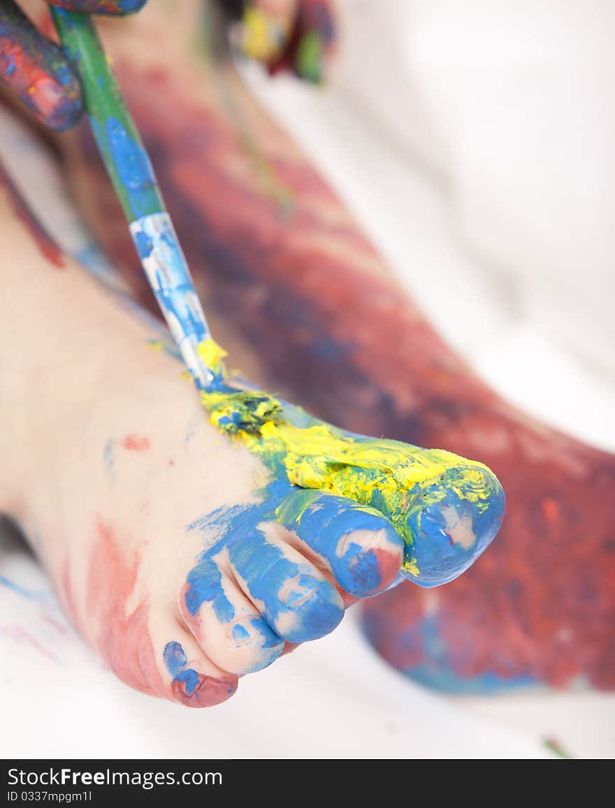 Beautiful baby covered in bright paint with paint brush. Beautiful baby covered in bright paint with paint brush