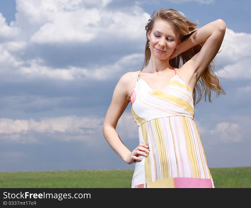 Outdoor portrait of a young lady on a blue cloudy sky background. Outdoor portrait of a young lady on a blue cloudy sky background