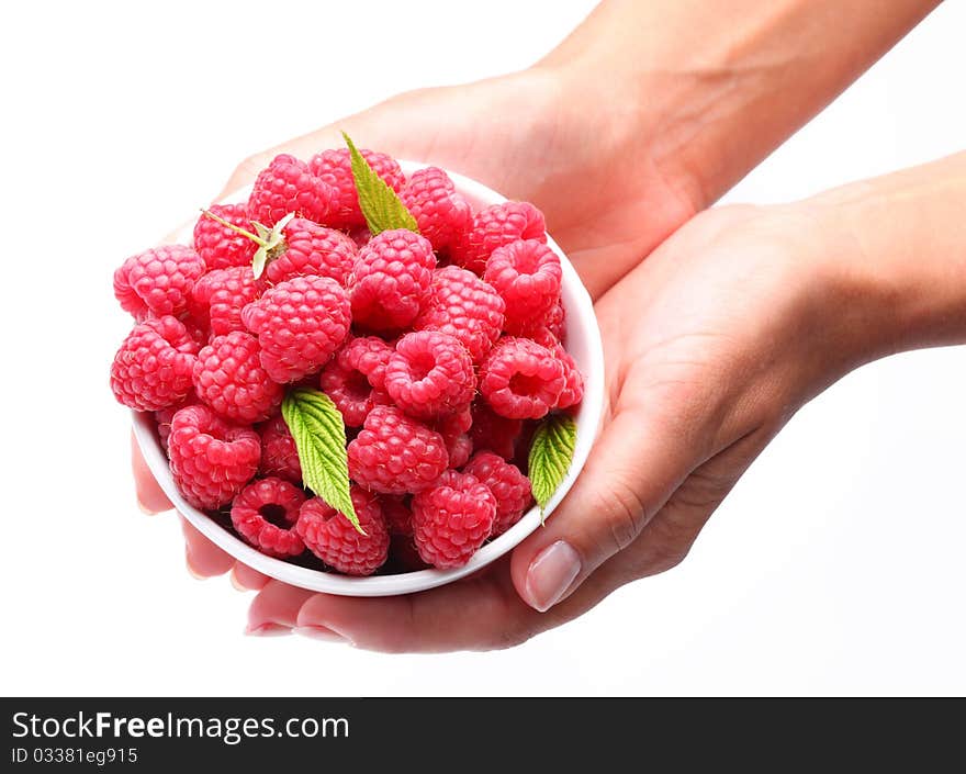 Crockery with raspberries in woman hands. Isolated on a white background.