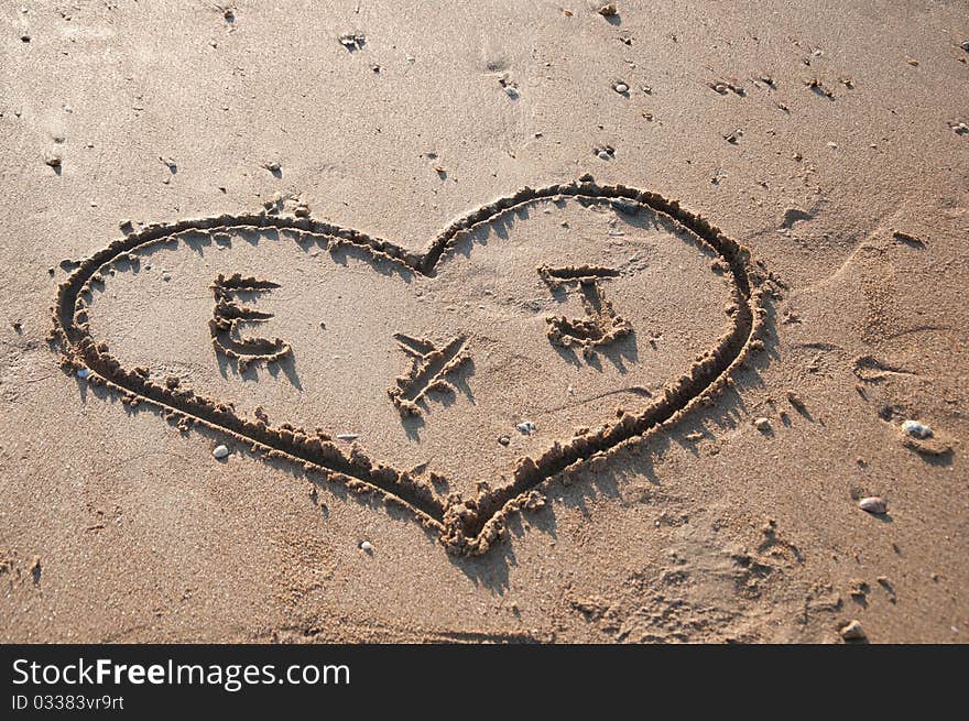 Heart drawn in the sand on the beach