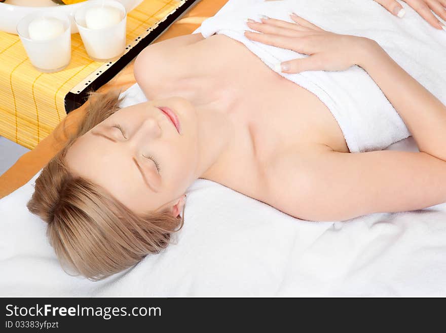 Woman in spa on white towel with blond hair