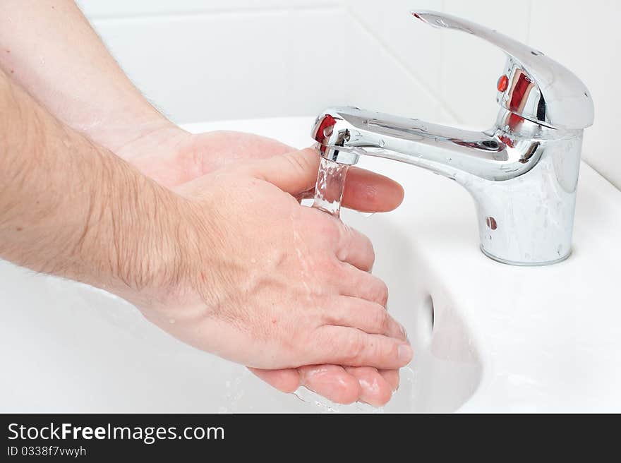 Close-up of human hands being washed under stream of pure water