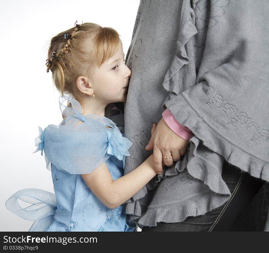 The girl kisses a stomach of the pregnant woman