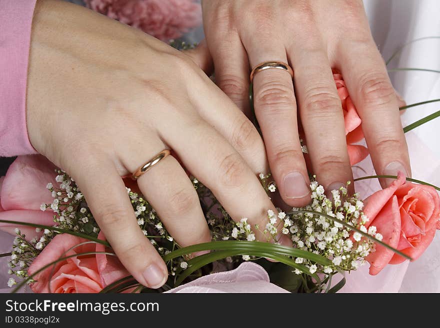 Hands are weaved and lie on a bunch of flowers