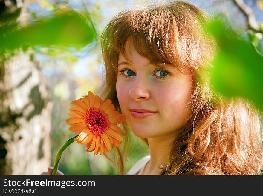 Smiling pretty young woman with flower gerber, standing outdoors in sunlight in spring. Smiling pretty young woman with flower gerber, standing outdoors in sunlight in spring