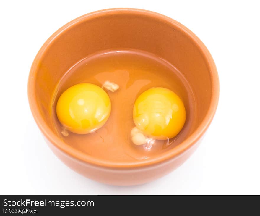 Two eggs are beaten out in a plate which is located on a white background