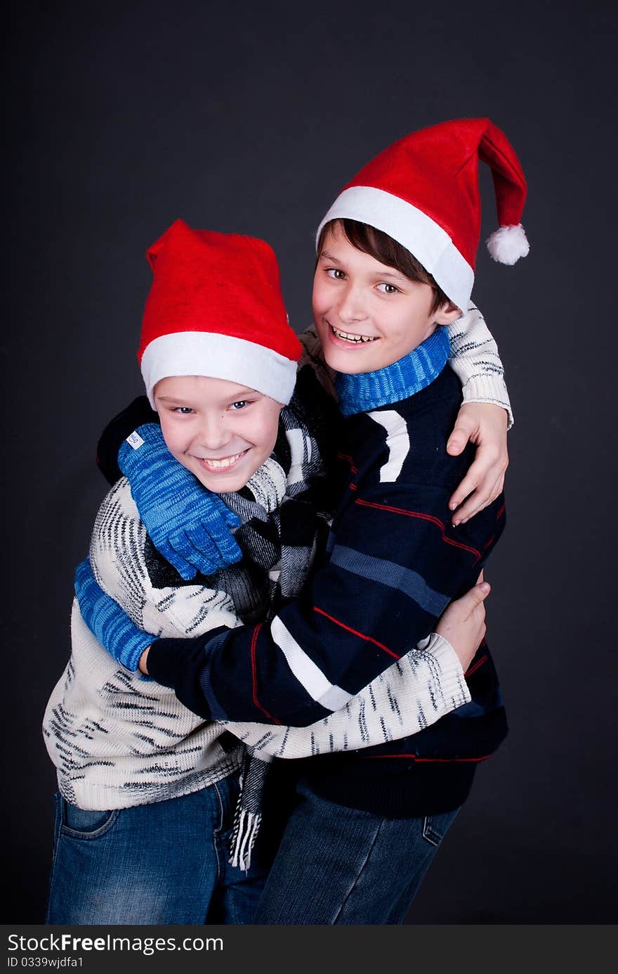 Two gay friend in New Year's hats on a dark studio background. Two gay friend in New Year's hats on a dark studio background