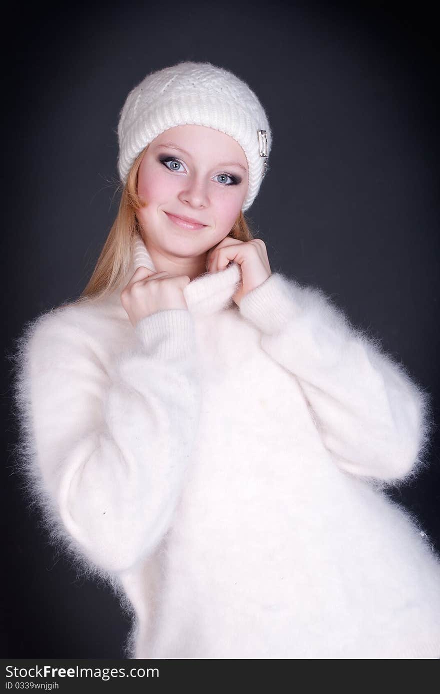 Portrait of the beautiful girl in winter cap on a dark background