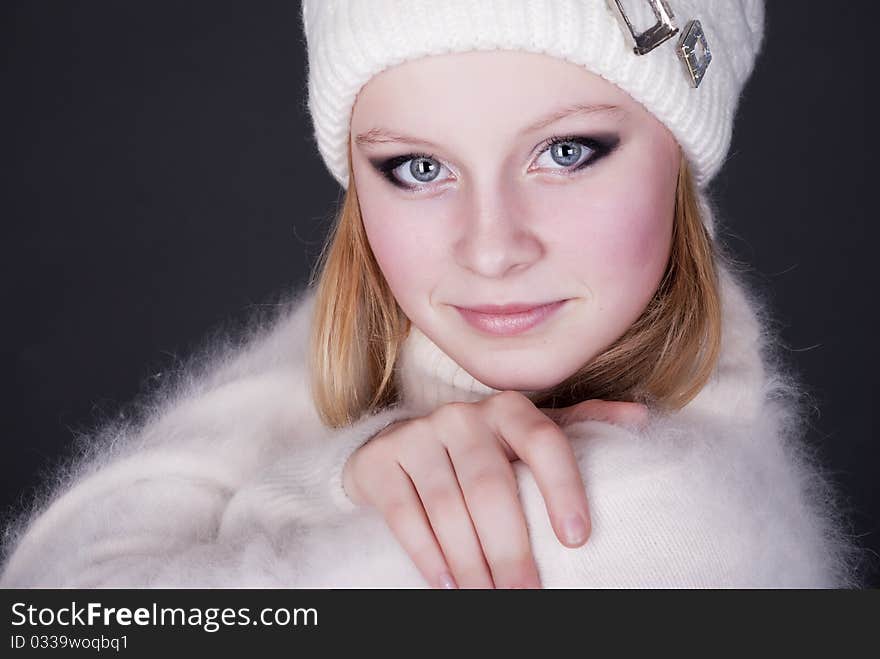 Portrait of the beautiful girl in winter cap on a dark background