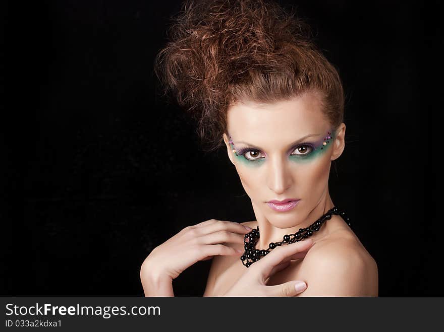 Portrait of young woman with creative make-up on black