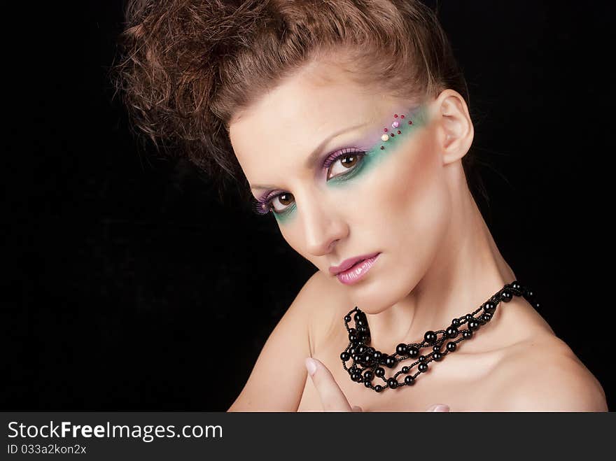 Portrait of young woman with creative make-up on black