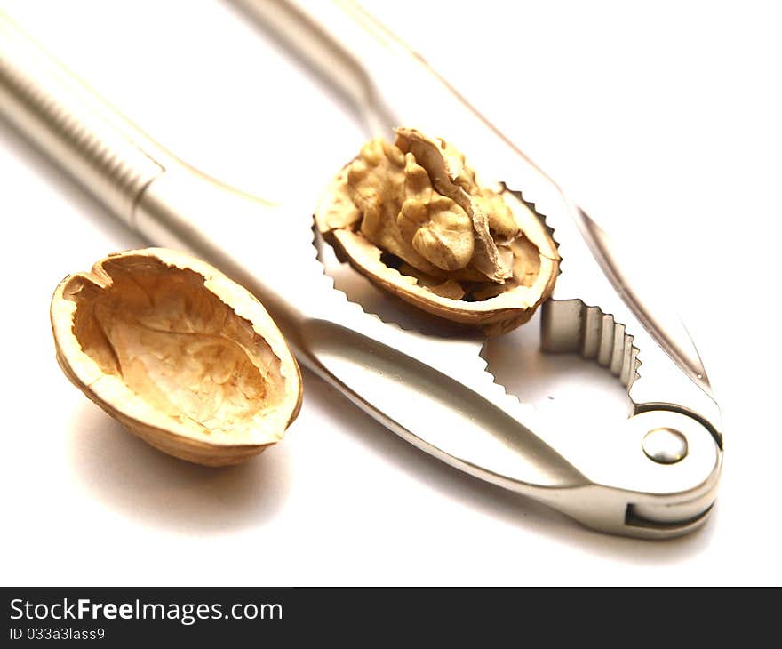 A walnut cracked by a nutcracker on white background. A walnut cracked by a nutcracker on white background